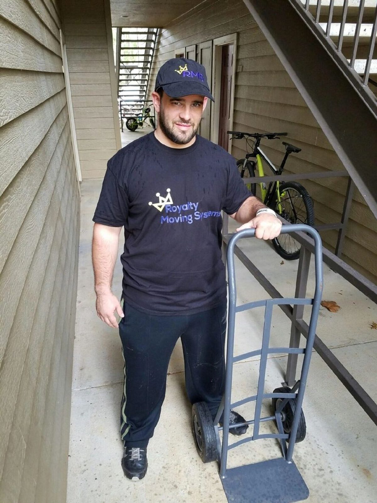 Royalty Moving owner moving items with a hand truck on a staircase