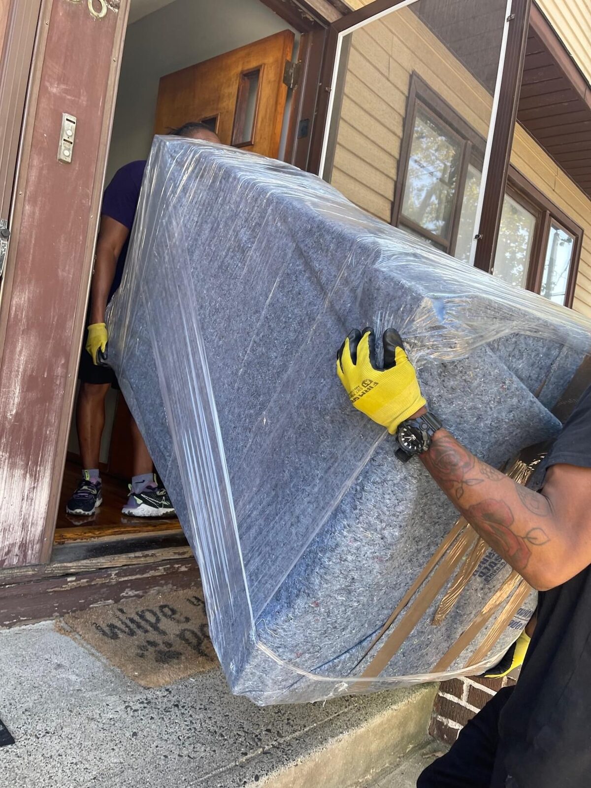 Royalty Moving team member carrying a wrapped mattress with care