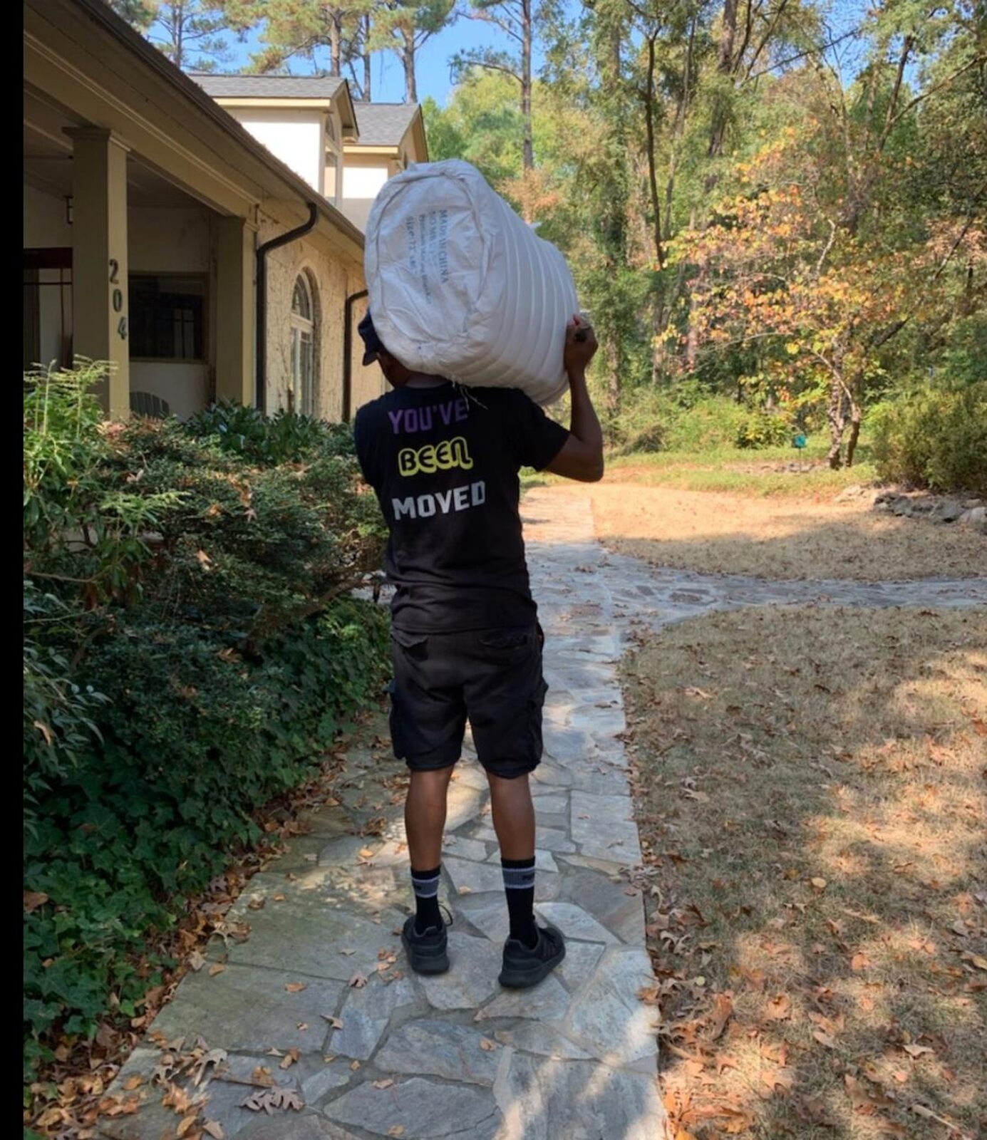 Royalty Moving crew carrying a wrapped item down the driveway to the truck